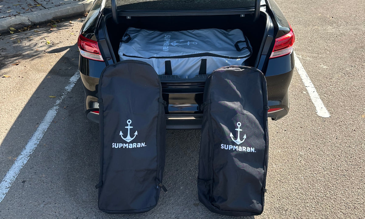 The fully disassembled Supmaran portable catamaran packed neatly into three carrying bags inside a car trunk.